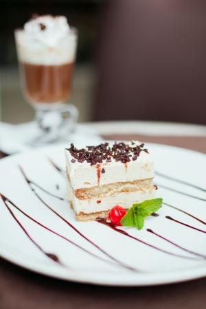 Tiramisu cake with a cherry and mint on white plate on table in restaurant  Piece of unhealthy calories fat food の写真素材