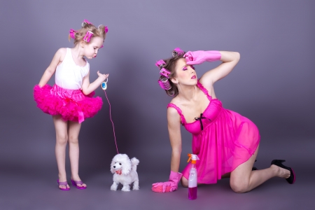 A beautiful young mother with her daughter in the form of cheerful housewives  Studio shot on a gray background  Seriesの写真素材