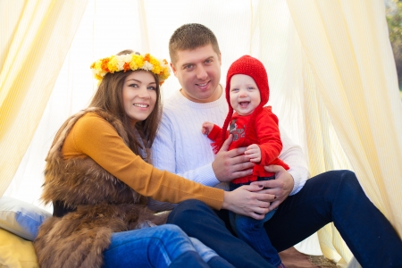 Happy young family with daughter posing sitting in tent in a parkの写真素材