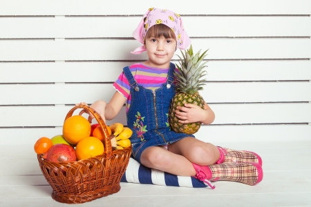 girl with basket of fruits over wall backgroundの写真素材