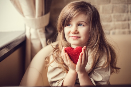 Valentine Day - dreaming cute child with red Heart in hands. の写真素材