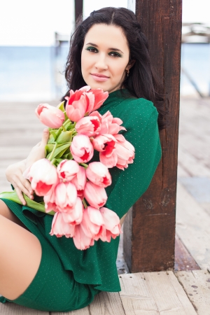 Beautiful young brunette woman with pink tulipsの写真素材