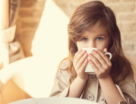 happy little girl indoors eating and smilingの写真素材