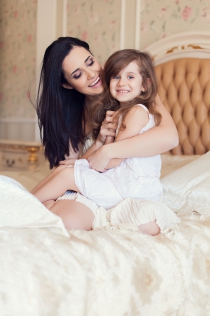 Portrait of mother and daughter in bed hugging and smiling. Morningの写真素材