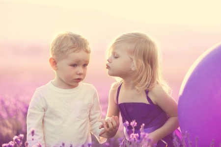 kids on lavender field at sunset, little girl kissing a boyの写真素材