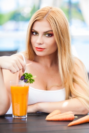Lovely smile relaxing woman drinking freshly squeezed carrot juice in a restaurantの写真素材