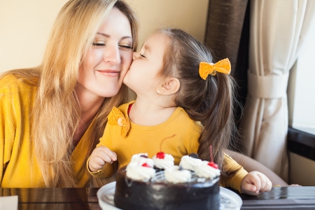 Mom and young daughter celebrating a birthday with cakeの写真素材