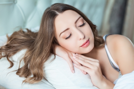 Portrait of young woman at the bed at early morningの写真素材