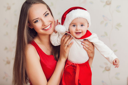 Portrait of happy mother and cute baby in suit of Santa's little helperの写真素材