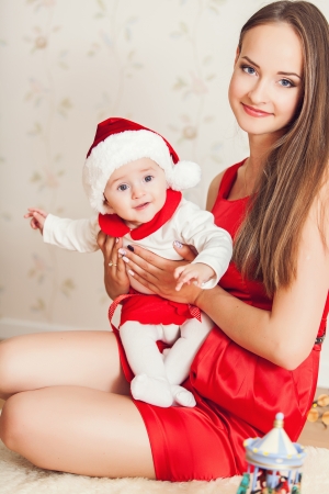 Portrait of happy mother and cute baby in suit of Santa's little helperの写真素材
