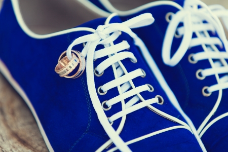 wedding details: blue footwear of groom with wedding rings on the lacesの写真素材