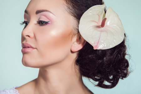 Close up portrait of stunning young model posing with white exotic flowerの写真素材