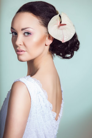 Close up portrait of stunning young model posing with white exotic flower