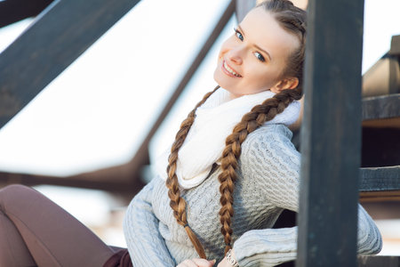 Portrait of lovely young female sitting on steps and smiling