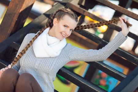 Portrait of lovely young female sitting on steps and smiling