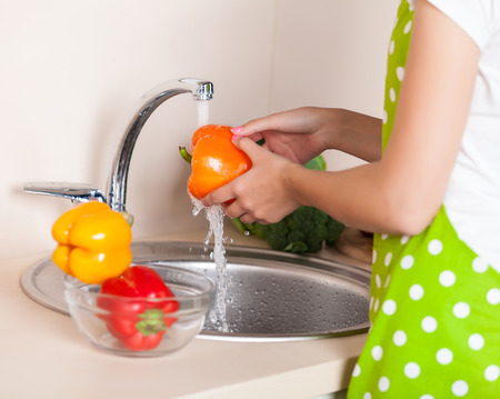 woman washing vegetables at kitchenの写真素材