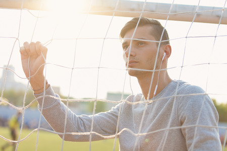 Portrait of a handsome young man standing on soccer field in sportswear on sunsetの写真素材