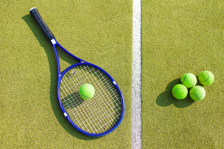 A tennis racquet and balls on a clay tennis courtの写真素材