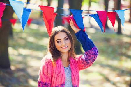 Young happy woman with colorful bunting flags against green treesの写真素材
