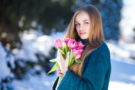 Young woman with a bouquet of tulips at the park. Snow in early springの写真素材
