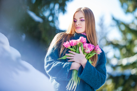 Young woman with a bouquet of tulips at the park. Snow in early springの写真素材