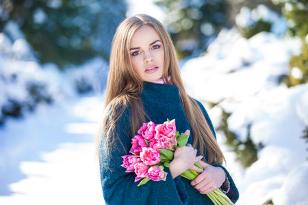 Young woman with a bouquet of tulips at the park. Snow in early springの写真素材