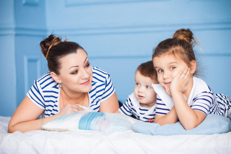 Mother and her happy children lying on a bedの写真素材