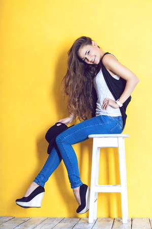 young woman wearing hat on a chair in studioの写真素材