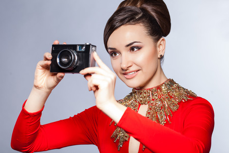 Elegant sensual young woman wearing red dress with retro photo cameraの写真素材