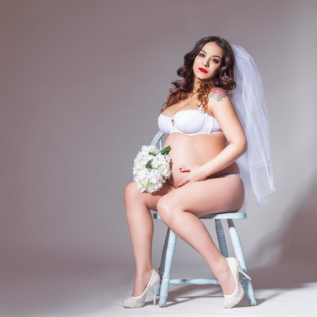 Beautiful pregnant bride wearing sexy lingerie in studioの写真素材