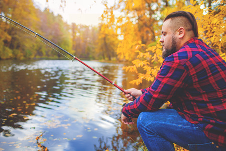 Young Man Fisherman bearded fishing with rod. River on backgroundの写真素材