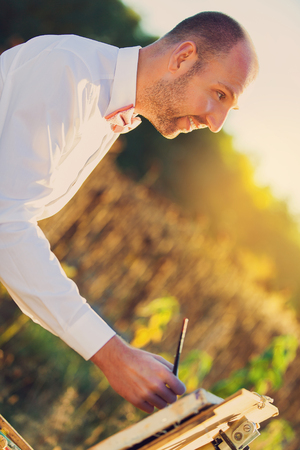 Groom paints a portrait of his beloved bride. Newly married wedding couple in a vintage setting. Sunsetの写真素材