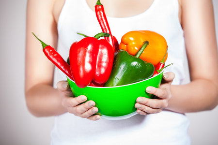 Cropped studio shot of a attractive woman holding up peppers
