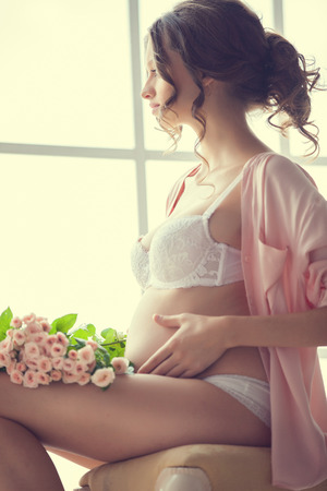 Home portrait of pregnant woman in lingerieの写真素材