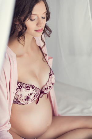 Home portrait of pregnant woman in lingerieの写真素材
