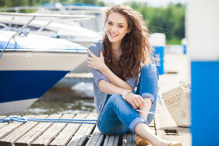 Young beautiful woman relaxing on the dock near the boat on a sunny dayの写真素材