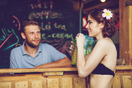 Beautiful sexy women at Tropical beach bar. Beautiful girl enjoying cocktail outside. Smiling happy Caucasian women on beach.の写真素材