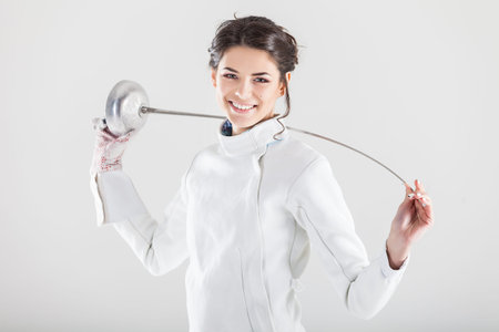 Portrait of woman wearing white fencing costume practicing with the sword
