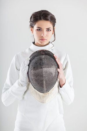 Portrait of woman wearing white fencing costume practicing with the sword