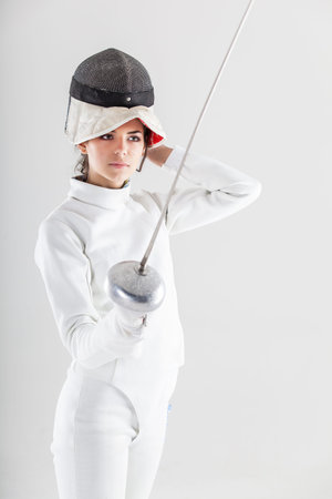Portrait of woman wearing white fencing costume practicing with the sword