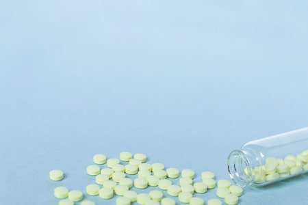 Yellow tablets and a glass bottle on a pastel blue background. Medicine, healthcare and the concept...