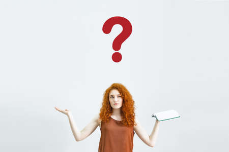 A Studio portrait of a sweet, puzzled, indecisive young woman shrugs, not understanding what happened. A rather attractive woman doubts in isolation on a white backgroundの写真素材