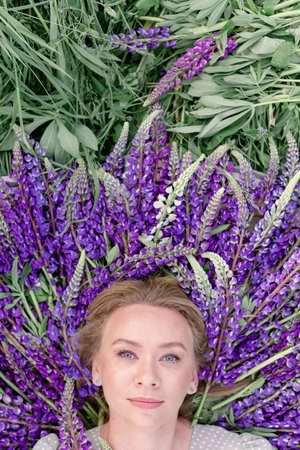 Close-up Portrait of a young beautiful girl woman lying on purple flowers with flowers around her...