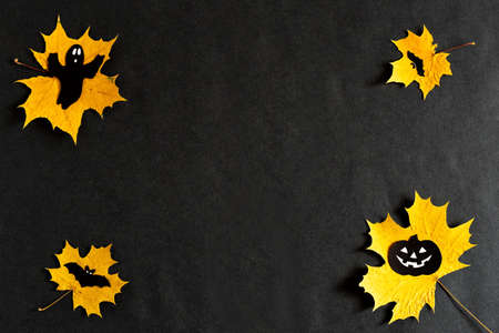 Pumpkin with eyes, Ghost, bats silhouettes made of black paper on yellow maple leaves on a black background. Dark background. Thanksgiving, the concept of Halloween. copyspace, Flatlay for your designの写真素材
