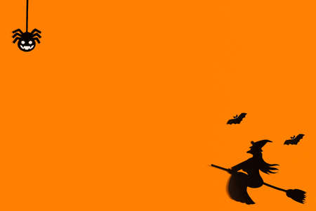 Silhouettes of a flock of bats and a witch flying on a broom made of black paper on an orange background. Halloween greeting template with copy space. Flat lay for your design. ready-made templateの写真素材