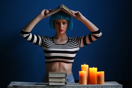 Girl posing with book on her head, blue wigの写真素材