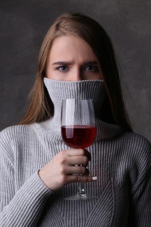 Girl posing with wineglass and covered face, girl with wineglass, high fashion look, beautiful girl, blonde girl, isolated, model in studio, long hair, close up, gray backgroundの写真素材