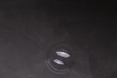 Fluying bubble in the air, soap bubble, bubble blower, blowing bubbles, ball, transparent bubble, close up, gray backgroundの写真素材