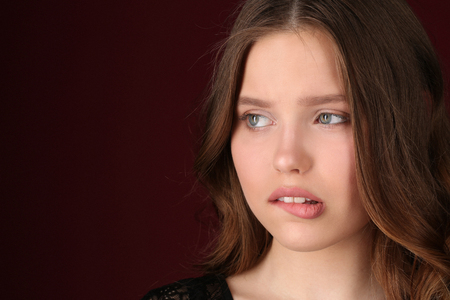 Lady bites her lip, girl in black dress, high fashion look, beautiful girl, smiling girl, isolated, long hair, perfect make-up, big lips, model in studio, close up, dark red backgroundの写真素材