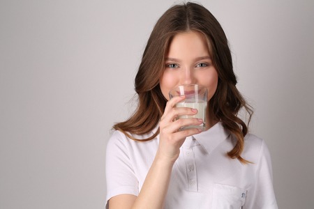 Girl tasting milk, girl in white T-shirt, high fashion look, healthy lifestyle, beautiful girl, smiling girl, isolated, perfect make-up, big lips, model in studio, close up, white backgroundの写真素材